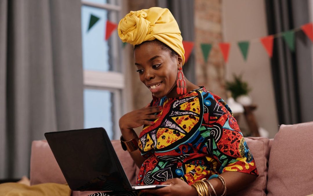 Femme noire souriante travaillant sur son ordinateur